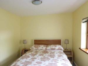 een slaapkamer met een bed, 2 lampen en een raam bij Ferrys in Portsalon