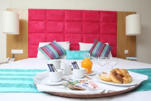 a breakfast tray with coffee and croissants on a bed at Odessa Beach Hotel in Protaras