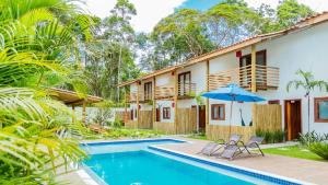 a house with a swimming pool and two chairs and an umbrella at Pousada Vila Mangaba in Arraial d'Ajuda