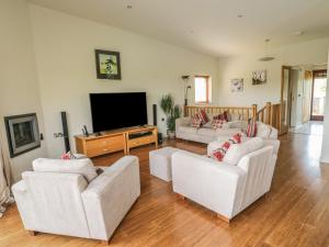 Una sala de estar con muebles blancos y un televisor de pantalla plana. en Boavista, en Carnforth