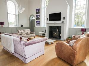 a living room with two couches and a fireplace at Capel Bryn Bachau in Pwllheli