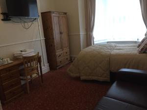 a hotel room with a bed and a dresser and a television at The Pines Guest House in Whitley Bay