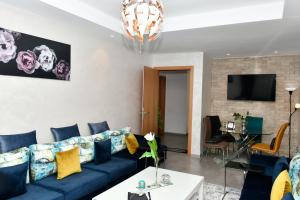 un salon avec un canapé bleu et une télévision dans l'établissement Appartement, à Temara