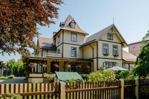 uma casa com uma cerca em frente em Villa Magonīte em Ventspils