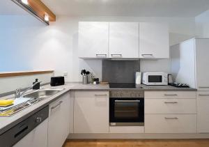 a kitchen with white cabinets and a sink and a microwave at Schönes Apartment im Herzen von Melle I home2share in Melle