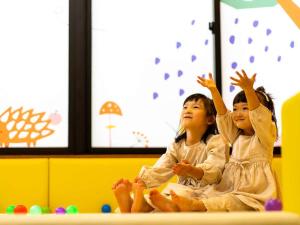 two young girls sitting on a table with their hands up at Hatsuneso Shinkan in Ureshino
