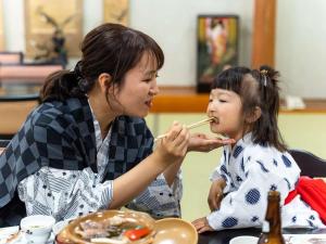 a woman feeding a little girl food with chopsticks at Hatsuneso Shinkan in Ureshino