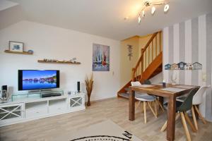 a living room with a dining room table and a television at Papillon Wohnung 04-6 in Boltenhagen