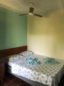 a bedroom with a bed with a ceiling fan at Pousada Encanto da Ilha in Praia de Araçatiba