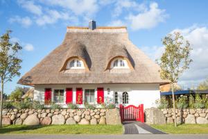 a house with a thatched roof with a red fence at Ferienhaus Haubenlerche 27 in Fuhlendorf