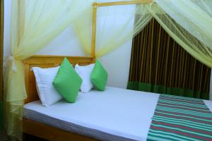 a bedroom with a canopy bed with green and white pillows at City Elephant Family Resort in Udawalawe