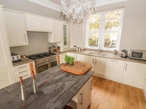 Una cocina con gabinetes blancos y una encimera de madera. en Beaulieu House, en Llandudno