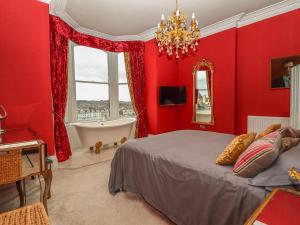 Un dormitorio rojo con una cama y una bañera. en Beaulieu House, en Llandudno