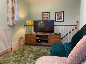 a living room with a flat screen tv on a wooden entertainment center at Ivythwaite Cottages in Windermere