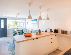 a kitchen with white cabinets and a dining room at Tide Pod in Wadebridge