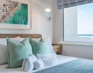 a bed with green and white pillows and a window at Tide Pod in Wadebridge