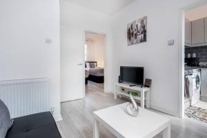 a white living room with a couch and a tv at Stunning 1-Bed Apartment in London Lewisham in London