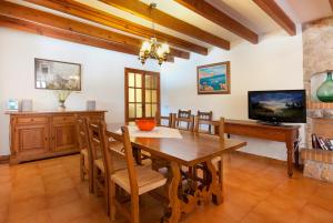 a dining room with a wooden table and a television at Villa Cal Apostol in Pollença