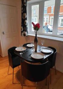 a table with chairs and a vase with flowers on it at 2 Bedroom House For Corporate Stays in Kettering in Kettering
