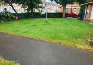 a grassy yard with a parking meter on the side of a street at 2 Bedroom House For Corporate Stays in Kettering in Kettering