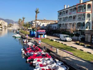 艾姆布里亞布拉瓦的住宿－Le Marinola Empuriabrava Port - 69m2- Vue canal principal - Plage centrale 400m，一群船停靠在建筑物旁边的河流中