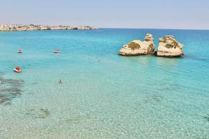 a group of people in the water near some rocks at HOTEL BARONE DI MARE in Torre dell'Orso