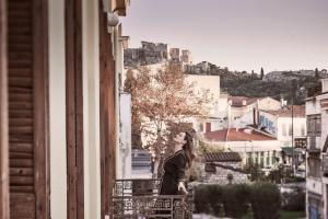 a woman standing on a balcony looking out of a window at Asomaton in Athens