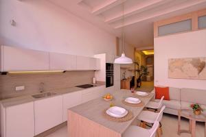 eine Küche mit weißen Schränken und einem Tisch mit Stühlen in der Unterkunft Elita Apartment in Los Llanos de Aridane