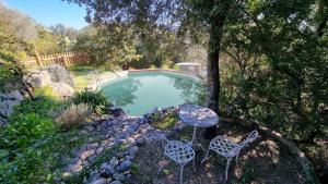 una piscina con dos sillas y una mesa en CASA SOPRANA - HAUT DE VILLA indépendant avec piscine et jardin privés - Independant TOP OF VILLA with private pool and garden, en Porto Vecchio