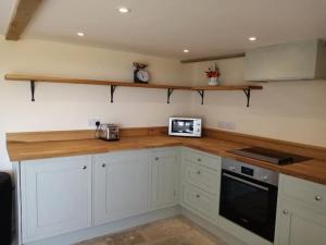 a kitchen with white cabinets and a wooden counter top at Rural getaway with a view - Old Spout Barn in Sedbergh