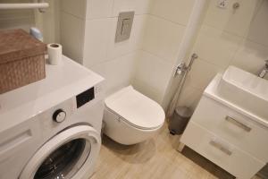 y baño blanco con aseo y lavadora. en Uroczy Apartament 38 m2 Tychy, Śląskie Ogrody, en Tychy