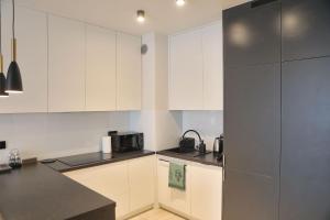 a kitchen with white cabinets and a refrigerator at Uroczy Apartament 38 m2 Tychy, Śląskie Ogrody in Tychy