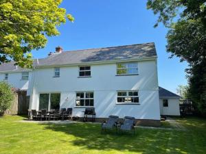 a white house with chairs in the yard at The Meadows St Teath, 4 bed sleeps 7 in Saint Teath