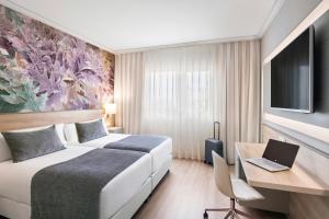 埃普拉特约布里加Salles Ciutat del Prat Barcelona Airport的一间配有床和带笔记本电脑的书桌的酒店房间