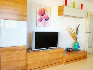een woonkamer met een televisie op een houten kast bij Apartamentos Ambar Beach (2-7º-D) in Calpe
