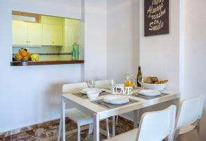 een eettafel met witte stoelen en een tafel met wijnglazen bij Apartamentos Nuevo Mexico (9º-C) in Calpe