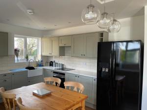 a kitchen with a wooden table and a black refrigerator at 2 bedroom detached bungalow with Hot Tub and secure garden and parking - Pet Friendly on 7 acres of land in Boston