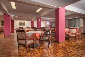 ein Esszimmer mit Tischen und Stühlen und rosafarbenen Wänden in der Unterkunft Qarmenqa Hotel in Cusco