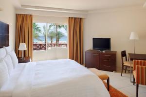 a hotel room with a large bed and a television at Naama Bay Promenade Beach Resort Managed By Accor in Sharm El Sheikh