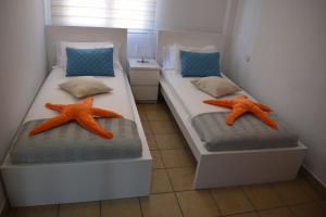 2 camas con objetos naranjas en una habitación en Suite del Mar Playa Esquinzo 1 Jandia Fuerteventura en Playa de Jandía