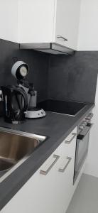 uma cozinha com armários brancos, um lavatório e um relógio em Appartement im Hasental em Garmisch-Partenkirchen