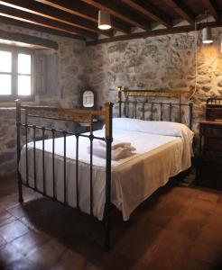 a bedroom with a bed in a room with stone walls at Casa Rural La Centenaria de Alaraz in Alaraz