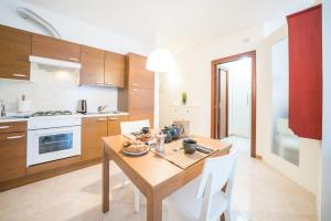 a kitchen with a wooden table and white chairs at Gardappartamenti Garibaldi City Centre in Desenzano del Garda