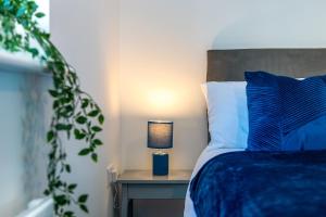 a bedroom with a blue bed with a lamp on a table at The Holt in Lincoln