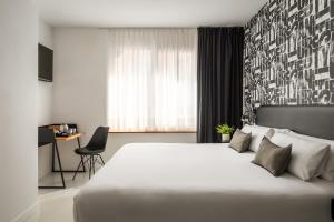 a hotel room with a bed, chair, table and window at Amari by Pillow in Bilbao