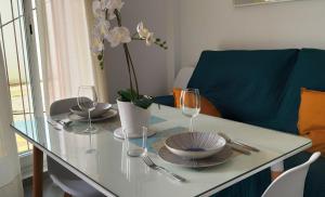 a dining table with glasses and plates and a blue couch at Chipiona Santuario de Regla Playa Bajo A in Chipiona +36 photos