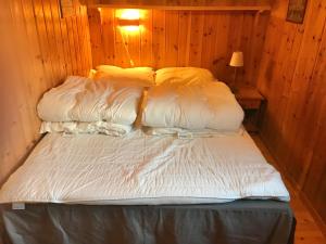 a bed with white sheets and pillows in a room at Haugland Gard in Haugaland