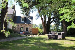 a stone house with a yard with chairs and trees at Ty Daou - Gîtes du Vieux Tilleul in Tréglamus