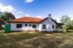 a white house with a red roof on a yard at Eldopalm Guesthouse in Eldoret
