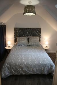 ein Schlafzimmer mit einem Bett und zwei Tischen mit Lampen in der Unterkunft Ty Daou - Gîtes du Vieux Tilleul in Tréglamus